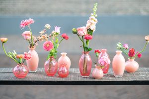 DutZ vaasjes uit de serie Nadiel in verschillende roze tinten. Alle vaasjes zijn gevuld met roze bloemen. De vaasjes staan op een rij naast elkaar op een tafel