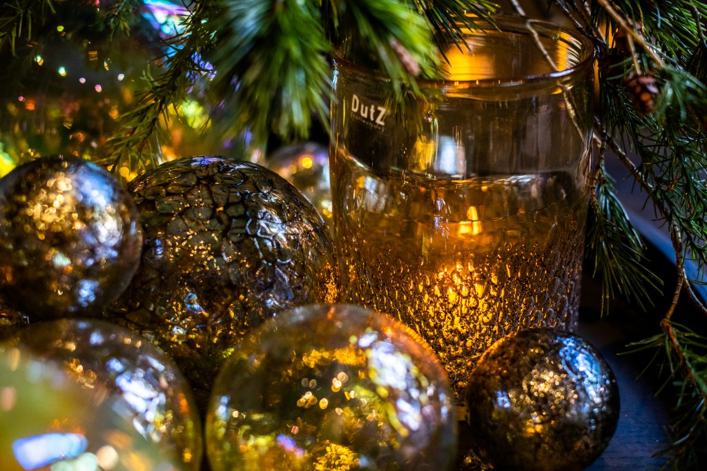 Decorative ballen in goudtinten en een kaarsenglas is de kleur amber