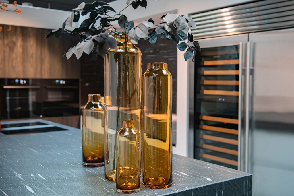 Vier hoge amber kleurige vazen variërend in hoogte op een keukenblok